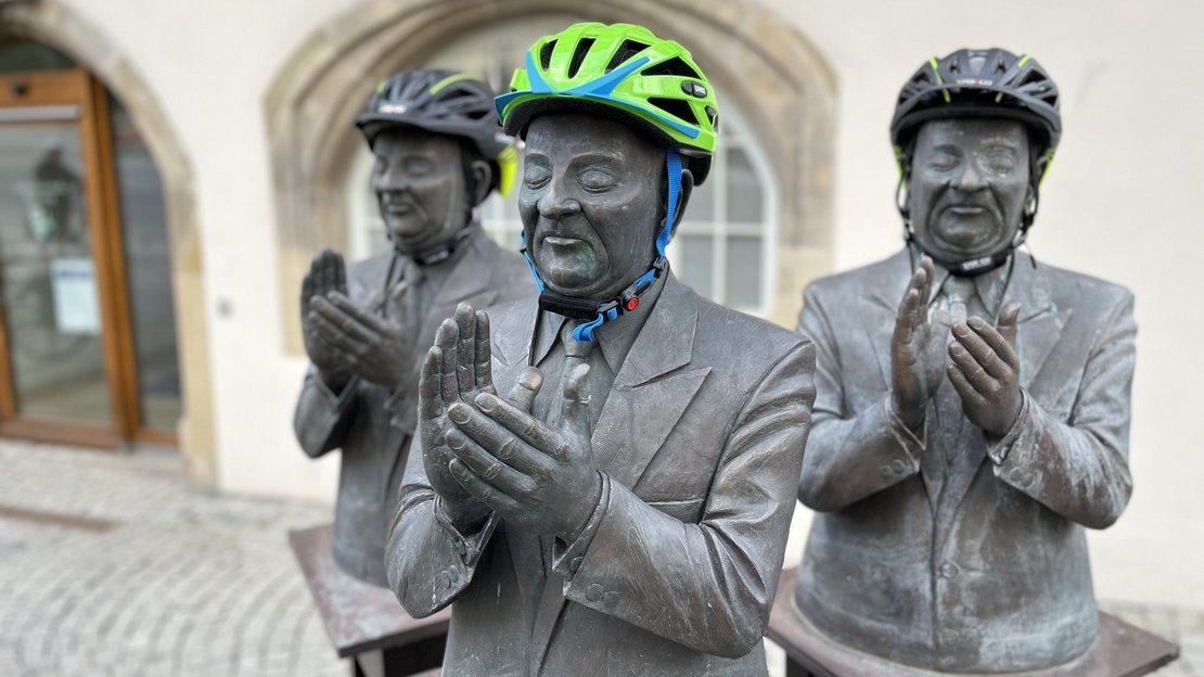Skulpturengruppe "Die Claqueure" vor dem Backnanger Rathaus. Die Köpfe der Skulpturen tragen Fahrradhelme.